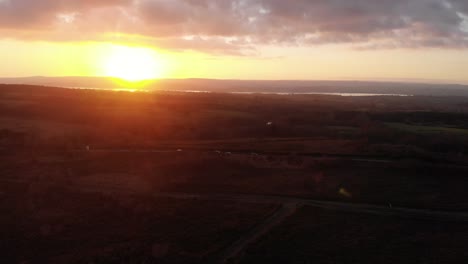 aerial left panning shot looking over woodbury common in devon england with a dramatic golden sunset