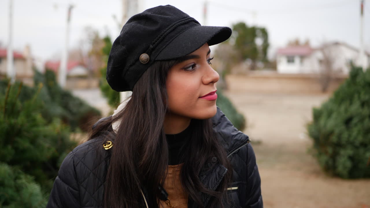 una hermosa mujer hispana comprando en un lote de árboles de navidad con coníferas verdes de abeto douglas en un vivero botánico de vacaciones