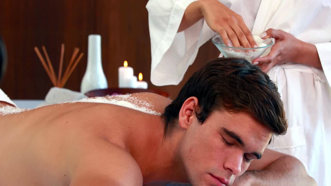 예쁜 남자가 소금 스크러브 치료를 받고 있습니다.