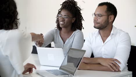 Smiling-people-shaking-hands-and-talking-during-meeting