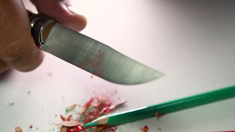 imágenes de manos afilando lentamente un lápiz y algunos lápices de colores con un cuchillo afilado