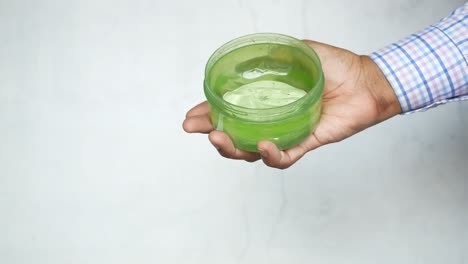 mano sosteniendo un recipiente de gel verde