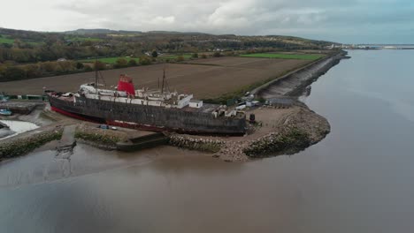 moored huge vessel on sandy coast, aerial fly forward view