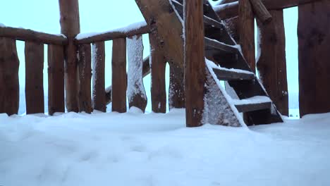 Pies-Masculinos-Subiendo-Escaleras-De-Madera-En-La-Plataforma-De-Observación,-Nevados-En-Invierno