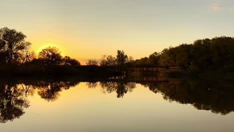 lovely peaceful sunset over the river. dark silhouettes of trees reflecting in the calm water.