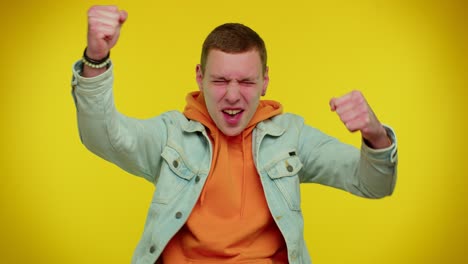 Teen-man-in-denim-jacket-shouting,-raising-fists-in-gesture-I-did-it,-celebrating-success,-winning