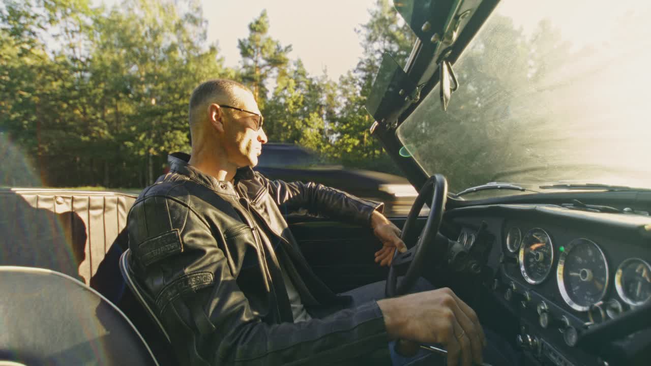 Man driving a classic convertible car on a sunny road