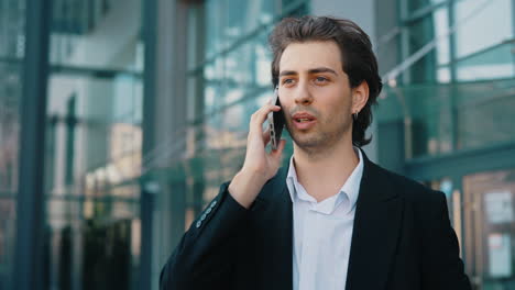 young businessman talking on phone outside modern building