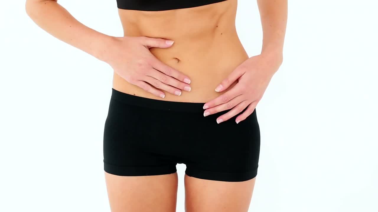 modelo en forma en sostén deportivo frotando su estómago