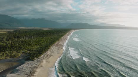 impresionante vista aérea del espectacular paisaje costero con el mar de tasmania, la remota playa de arena y el paisaje cubierto de árboles en el desierto de bruce bay, south westland, nueva zelanda aotearoa