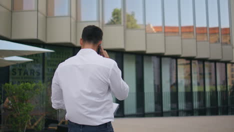 successful entrepreneur making call walking in modern city back view. man going