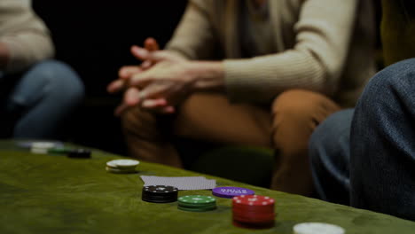 side view of the hands of a woman who take playing cards and poker chips on the table