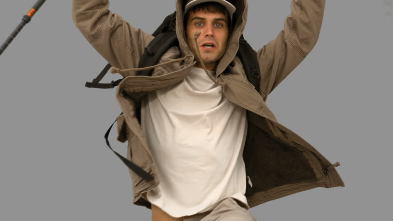 Man with a hiking stick jumping on grey screen