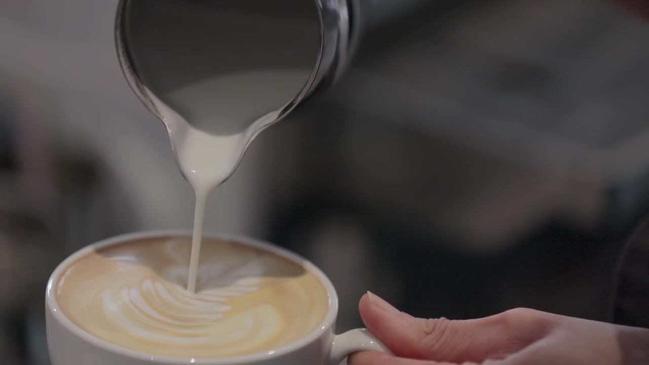 Versamento di latte in una caffetteria specializzata, per creare latte art.