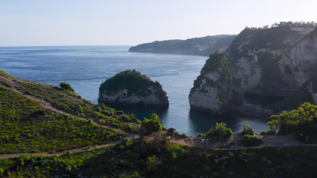 turistas caminando cerca de enormes rocas en el mar azul en la playa de suwehan, bali, indonesia