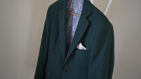 dark green suit jacket with a patterned lining and a pocket square, hanging on a hanger