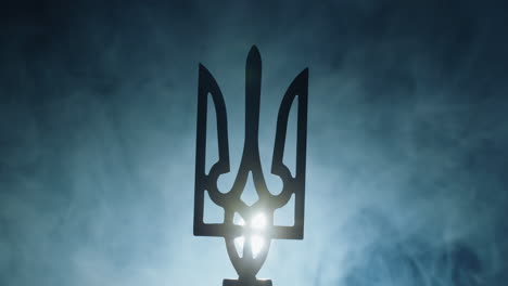 el escudo de armas de ucrania en la niebla, iluminado por un reflector