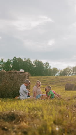 familia feliz disfrutando de un picnic en una manta en el campo abierto, rodeado de balas de heno, el calor de la luz del sol con la llamarada de la cámara añade a la atmósfera pacífica, un sombrero descansa en una bala de heno