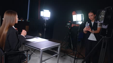 Studio backstage footage. Video with a female reporter is recorded in studio by cameraman and girl.