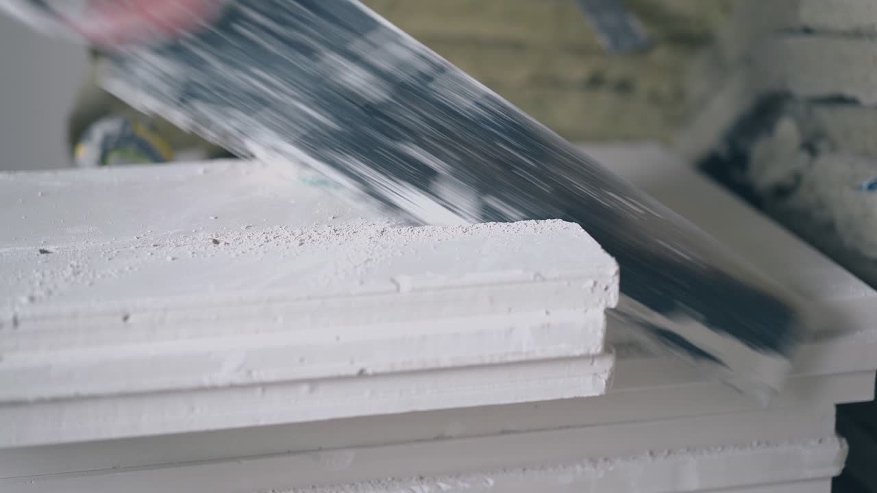 skilled painter in gloves saws white gypsum plasterboard
