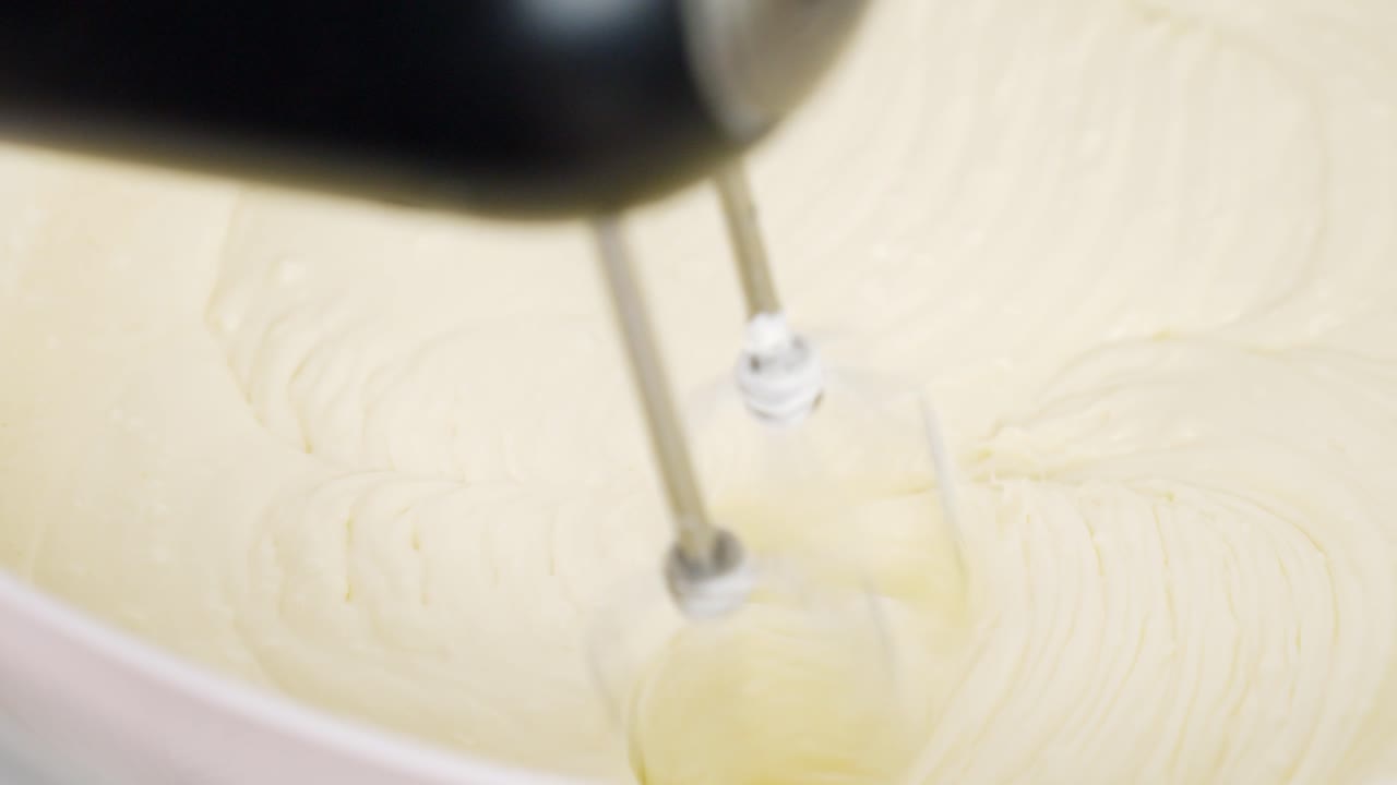 Whipping egg whites until stiff peaks form for tiramisu dessert in mixing bowl