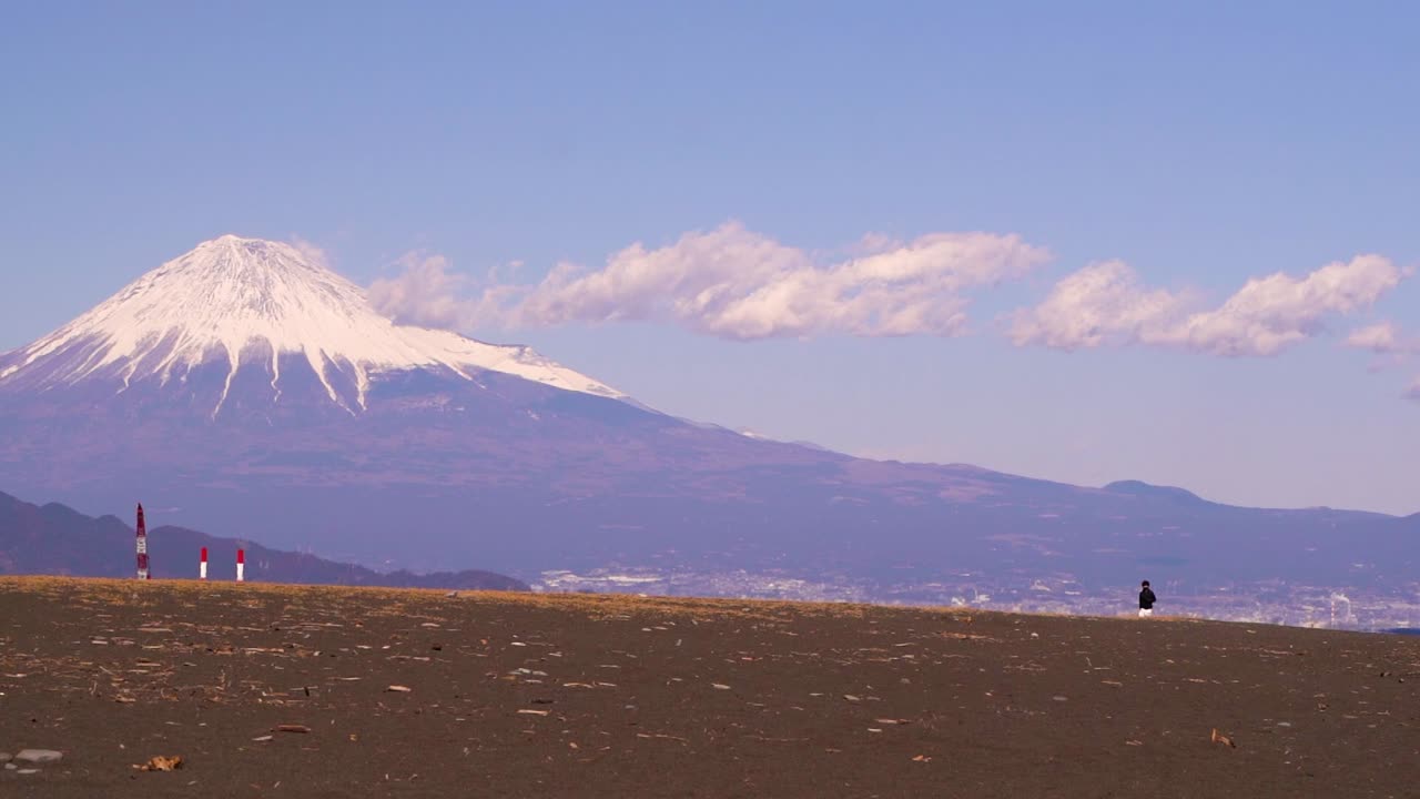 persona caminando en la playa cerca del monte fuji mostrando la escala de la montaña