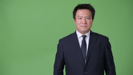 mature japanese businessman against green background