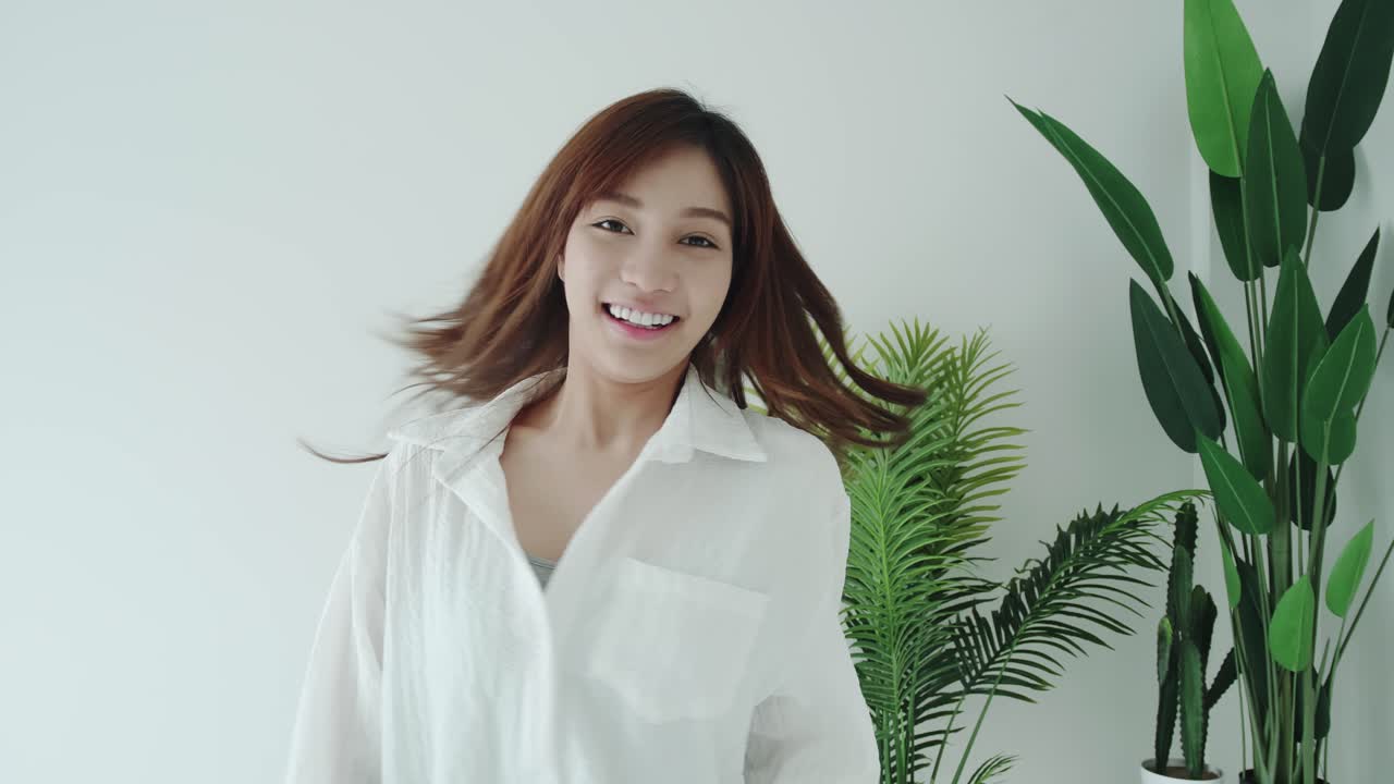 흰색 셔츠를 입은 아시아 여성의 슬로우 모션 추적은 흰색 방에서 좋은 느낌을 줍니다.