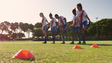 Female-soccer-players-stretching-their-legs-on-soccer-field.-4k