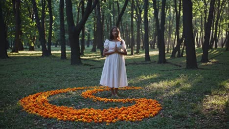 young woman performing a healing ritual within a vibrant spiral of orange flowers, surrounded by a tranquil forest, fully embracing the energy of nature and fostering inner peace