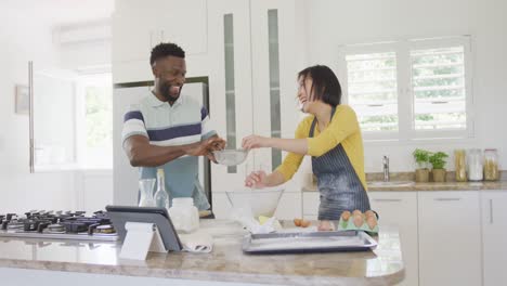 Happy-diverse-couple-wearing-apron-and-baking-in-kitchen