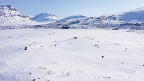 aerial view of small town by frozen lake in snowy mountain landscape