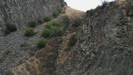 Low-flight-past-twisted,-contorted-volcanic-basalt-column-rock-cliff