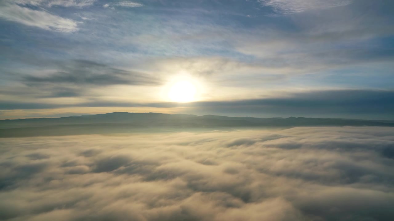 Vista aerea del sole che splende sopra una fitta nebbia mattutina.
