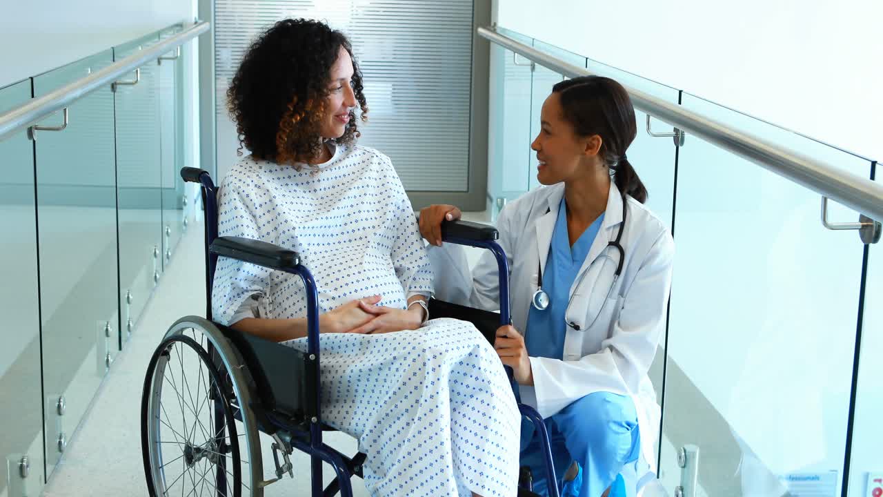 Doctor interacting with pregnant woman in corridor