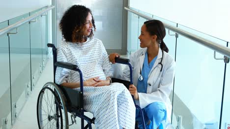 Doctor-interacting-with-pregnant-woman-in-corridor