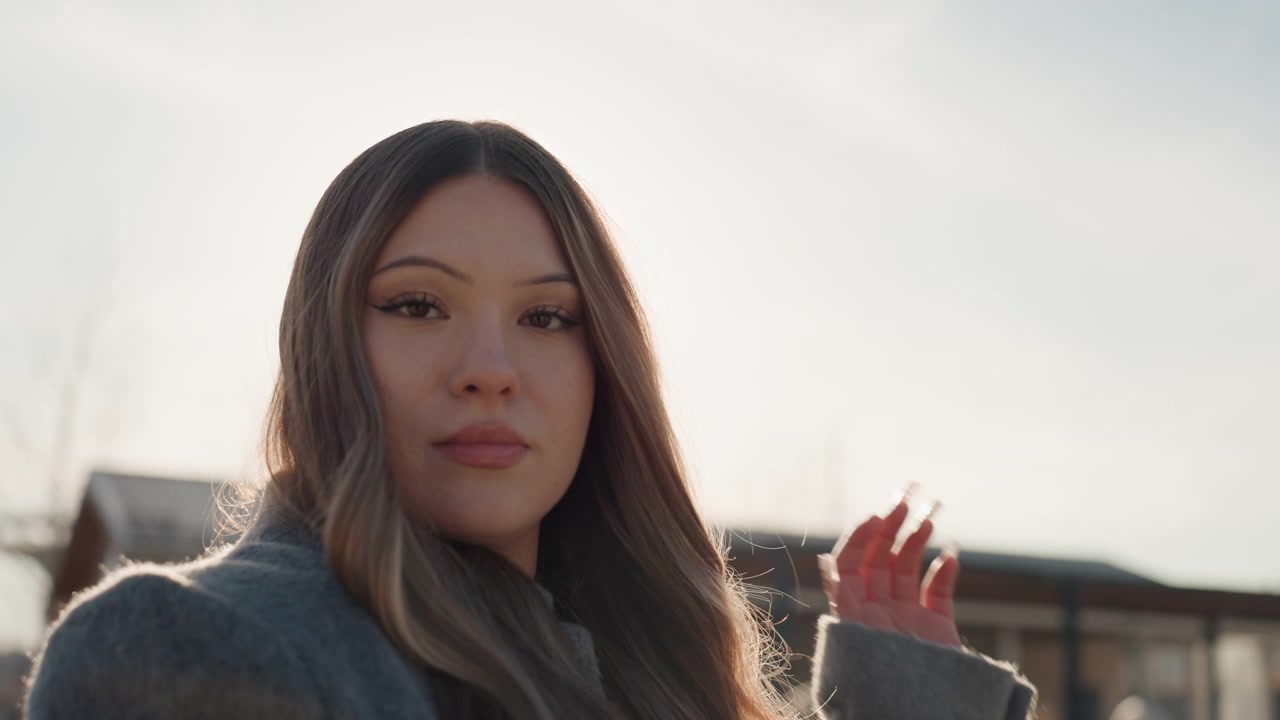 Hermosa escena de atardecer con mujer elegante. Mujer encantadora toma una foto con el cálido horizonte de la ciudad de fondo. Dama elegante captura una foto durante el atardecer reflejado sobre el horizonte urbano con suaves efectos bokeh.