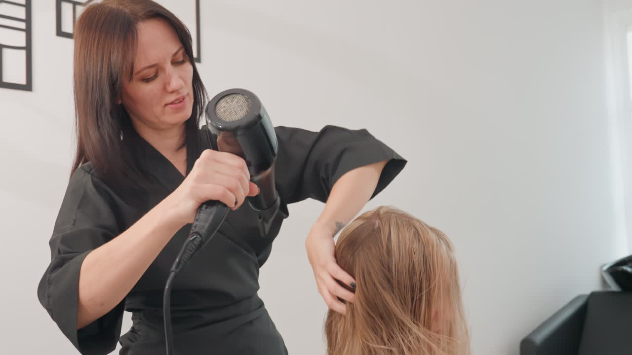 asciugacapelli professionale che modella i capelli bagnati dando volume e forma finale, mani che guidano il flusso d'aria e la tensione, cliente seduto sulla sedia mentre il professionista dimostra la tecnica di rifinitura, pareti luminose dello studio, messa a fuoco