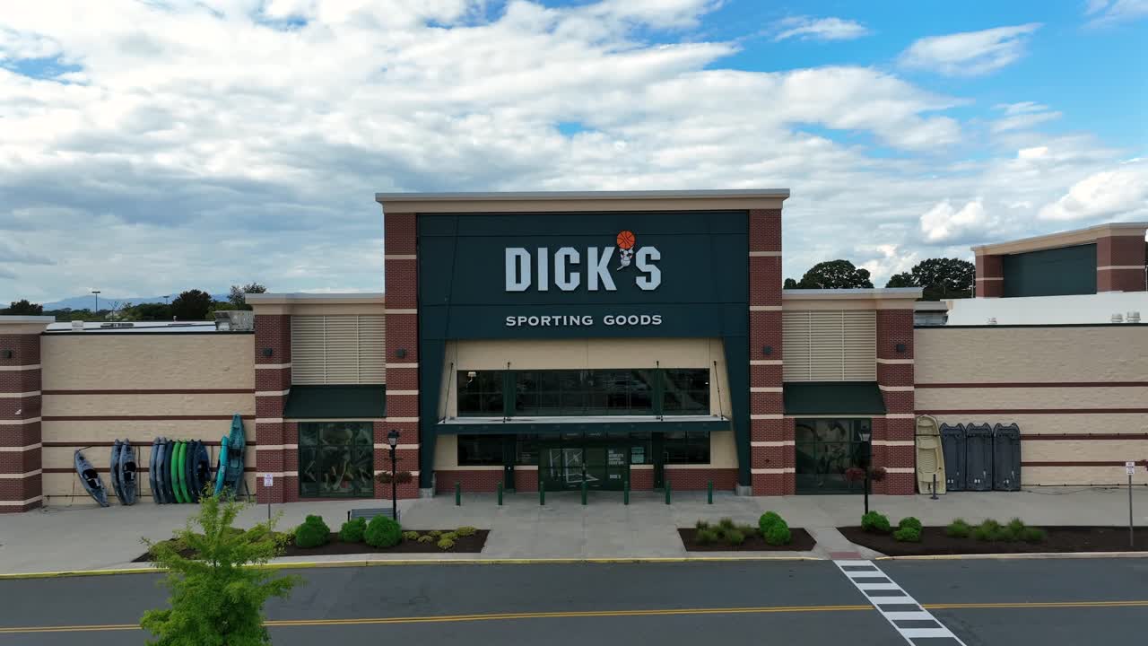 Dicks Sporting Goods Store in american shopping center. Driving car on street during cloudy day in summer. Rising drone wide shot. River Ridge Mall, Virginia.