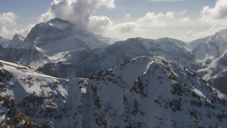 Aerial-dolly-shot-overhead-a-mountain-peak-revealing-the-large-snowy-alps-in-italy