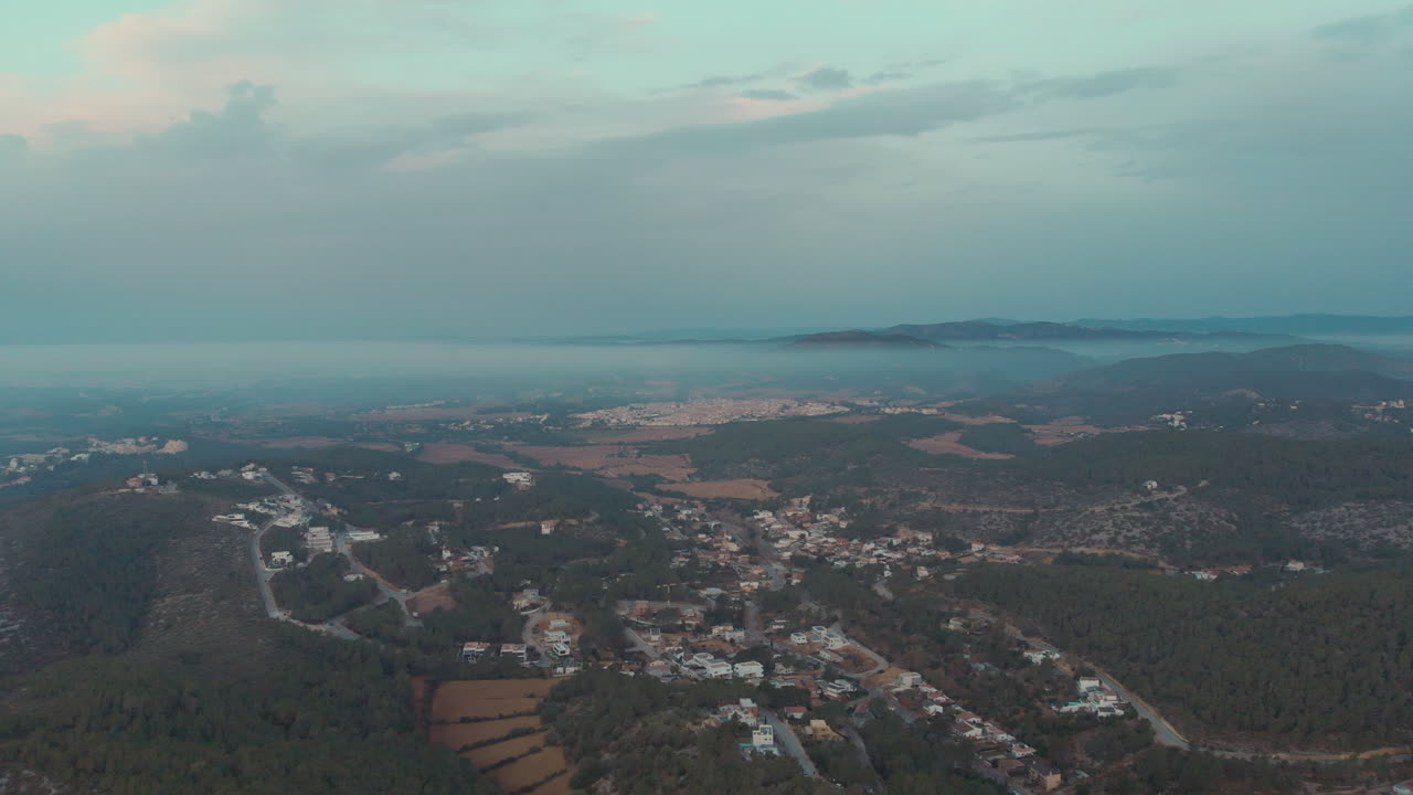 푸른 산과 봉우리 주변의 안개 낀 구름 사이에 싸인 집들이 있는 풍경