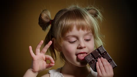 Portrait-of-teen-smiling-child-kid-girl-with-milk-chocolate-bar-showing-thumb-up-gesture,-ok-sign