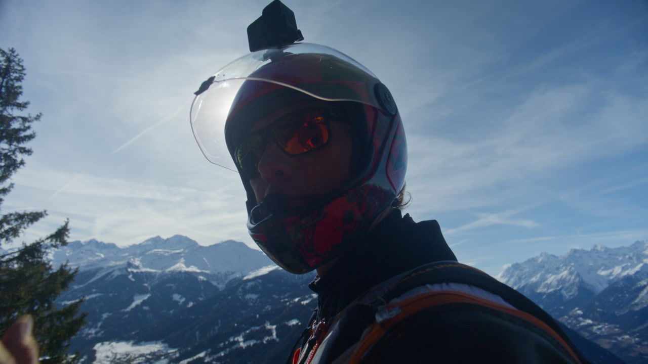Wingsuit BASE jumper flying over Verbier surrounded by alpine mountains with snow-covered peaks. High-speed flight, dramatic scenery, and cinematic extreme sports action in the Swiss Alps.