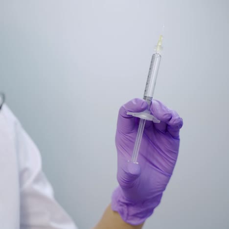 a beautician in purple gloves is holding an injection of a botulinum toxin in her hand at a medical cosmetology center. close-up. preparation to the procedure