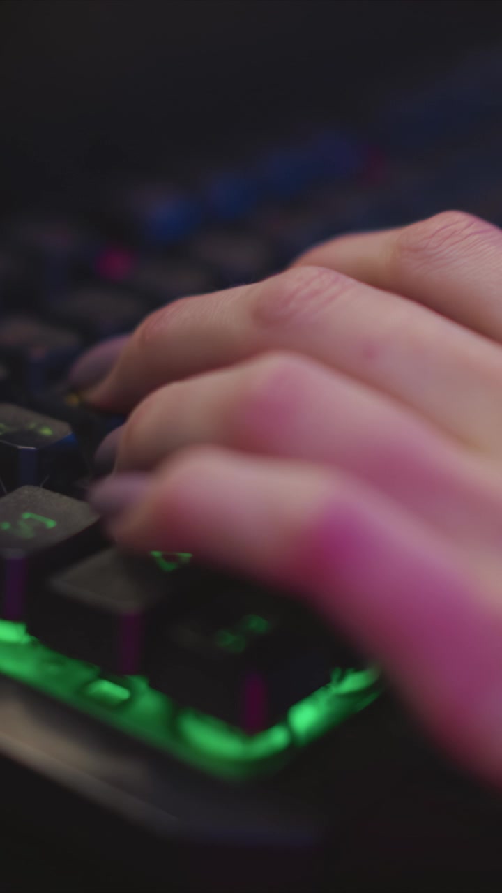 Close up view of hands typing on backlit keyboard with green illumination. focus remains consistently on hand movements and key presses highlighting detailed skin texture and finger