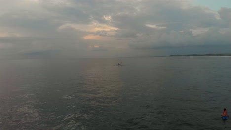 Wide-shot-of-fishing-boat-at-calm-sea-near-Bali-Indonesia,-aerial