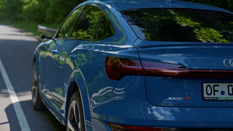motion of modern e-tron car. light blue audi model driving on a highway. luxury electronic car at sunlight. test drive of e-tron audi.