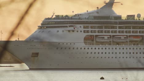 cruise ship exits port at sunset, passengers moving on deck medium telephoto shot