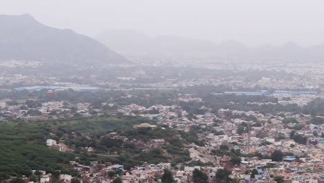 La-Ciudad-Llena-De-Gente-Alberga-Un-Paisaje-Con-Un-Fondo-De-Montaña-Brumoso-Por-La-Mañana-Desde-Un-ángulo-Plano