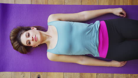 Retrato-Aéreo-De-Una-Mujer-Joven-Haciendo-Yoga-En-Un-Piso-De-Madera